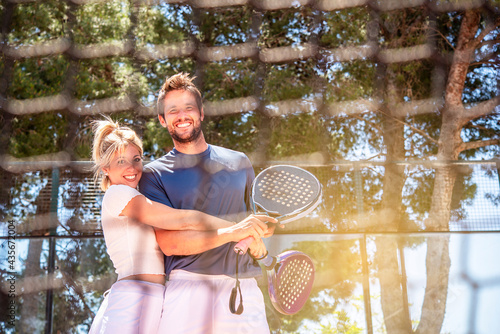 man and a woman happily hug each other after a game of padel in a sunny day