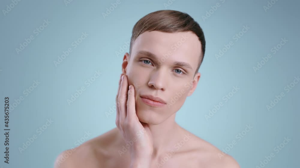 Portrait of handsome man touching face with one hand while looking to camera .Crop view of male model with light blue eyes posing . Concept of cosmetology, skincare. Portrait of handsome man touching face with one hand while looking to camera .Crop view of male model with light blue eyes posing . Concept of cosmetology, skincare.