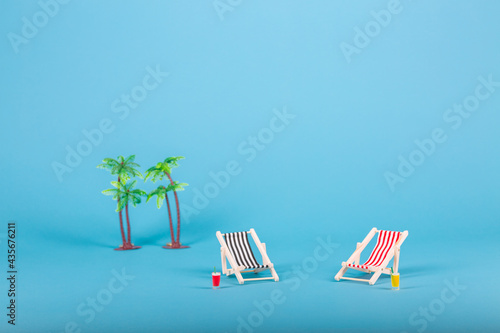 Beach chairs isolated and two palms on blue background
