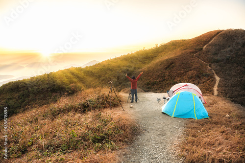 Man traveler Taking photo on top of mountains near of tent camping gear  Hiking at Kowloon Peak   Fei Ngo Shan   Hong Kong  People living healthy active lifestyle outdoors