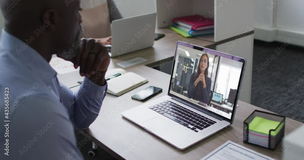 African american senior man having a video call with female colleague on laptop at office