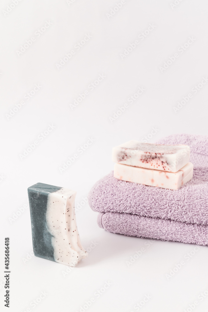 Handmade soaps on purple towels on a white background. Minimal cosmetics concept. Handmade soaps on purple towels on a white background. Minimal cosmetics concept.