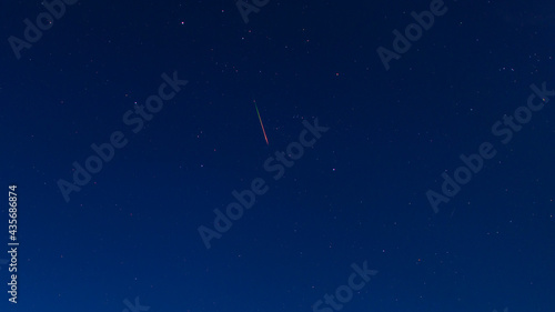 Bright red-green meteor of Perseid flow in the night sky