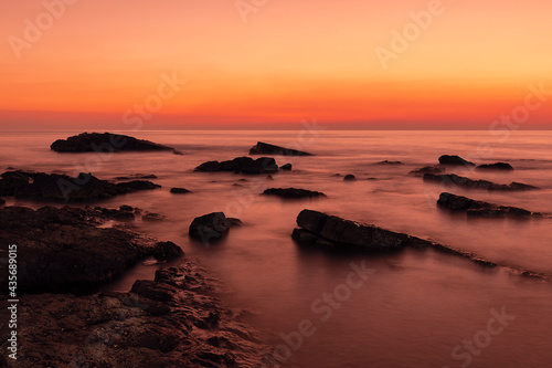 Silhouettes of rocks in the water of sea against the sunset sky