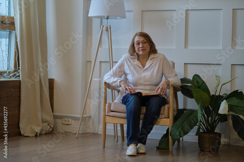 portrait of an elderly woman sitting on a chair at home. photo
