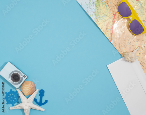 Summer travel flet lay background, made with different shells, camera, modern colorful sunglasses, map and white envelope.   Creative copyspace. photo