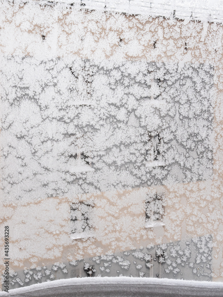 Fototapeta premium frozen home window with snowdrift on frame in city