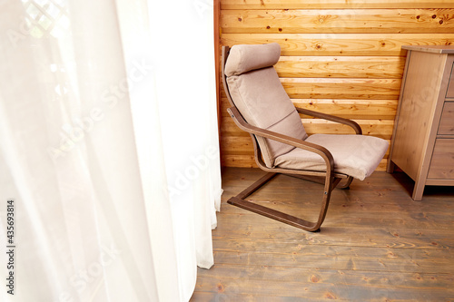 interior of wooden house. Comfortable chair near window with elegant curtains in room © leravalera89