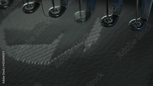 Close up of a commercial embroidery machine sewing a logo on leather.