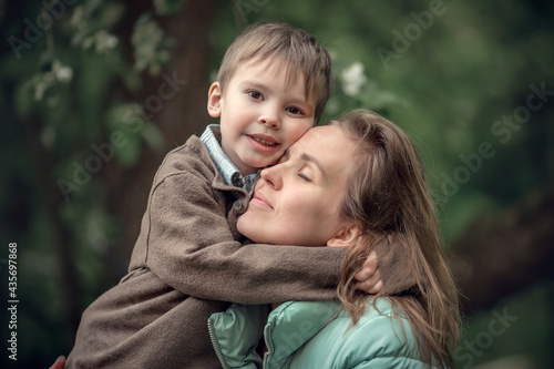 Cute little boy is hugging his blond mother. Image with selective focus and toning.