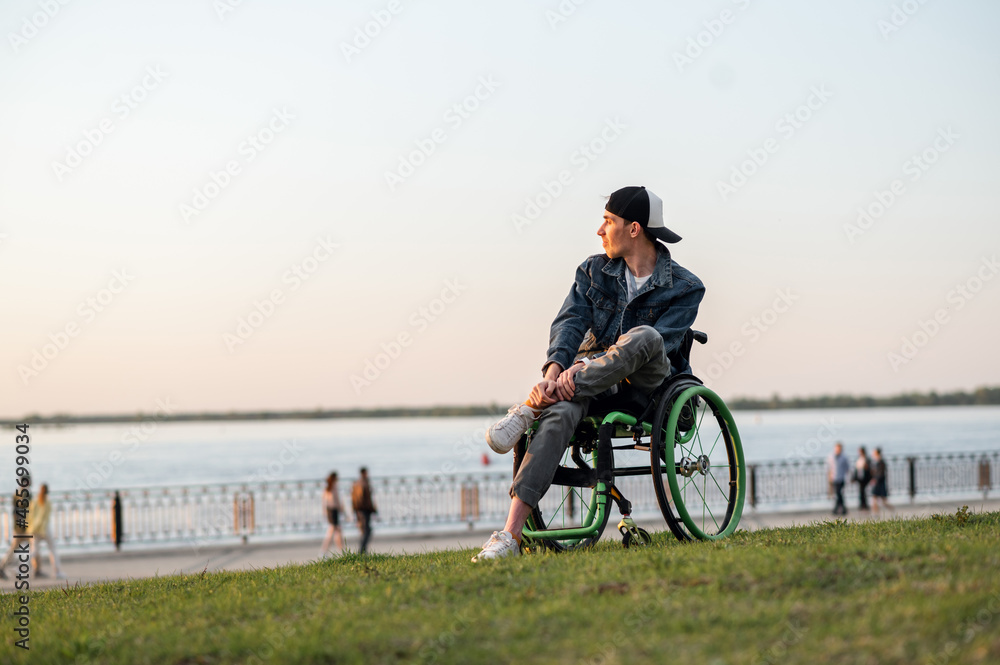 Fototapeta premium a young man in a wheelchair, walking around the city, enjoying the sunset