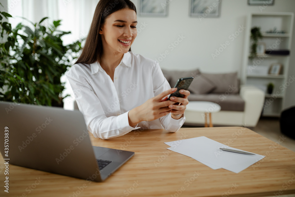 Side view of college student studying on laptop and using phone at home. Side view of college student studying on laptop and using phone at home.
