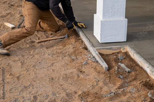 Φωτογραφία Worker removing wood form from edge of new concrete cement sidewalk, at a construction job site