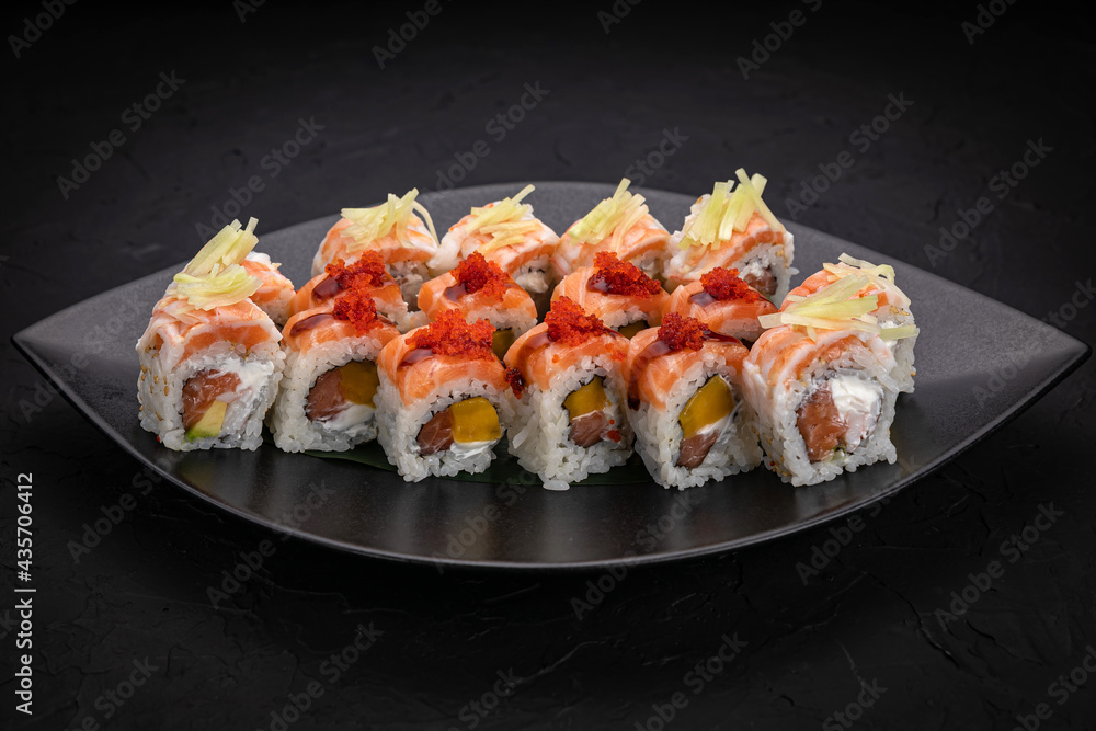 Japanese cuisine. Rolls on a black plate on a wooden table Japanese cuisine. Rolls on a black plate on a wooden table