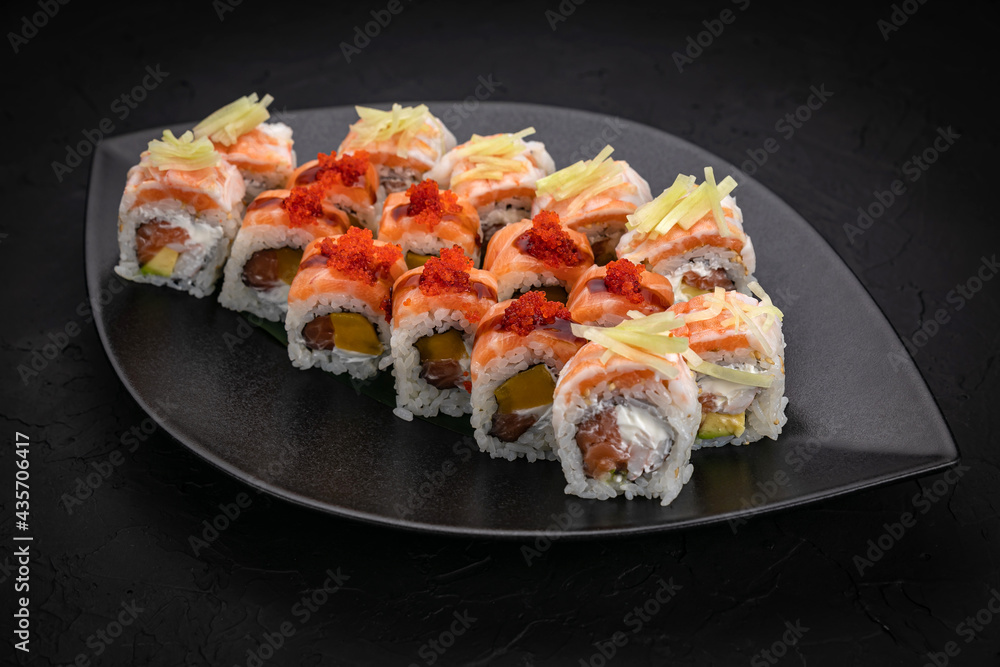 Japanese cuisine. Rolls on a black plate on a wooden table Japanese cuisine. Rolls on a black plate on a wooden table