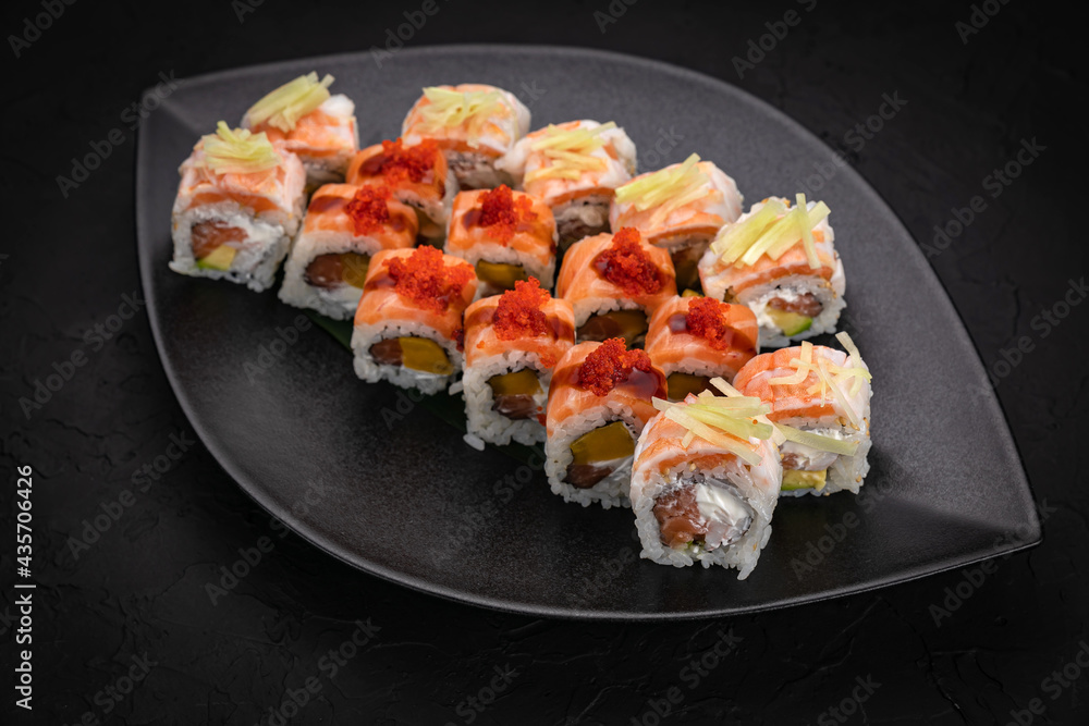 Japanese cuisine. Rolls on a black plate on a wooden table Japanese cuisine. Rolls on a black plate on a wooden table
