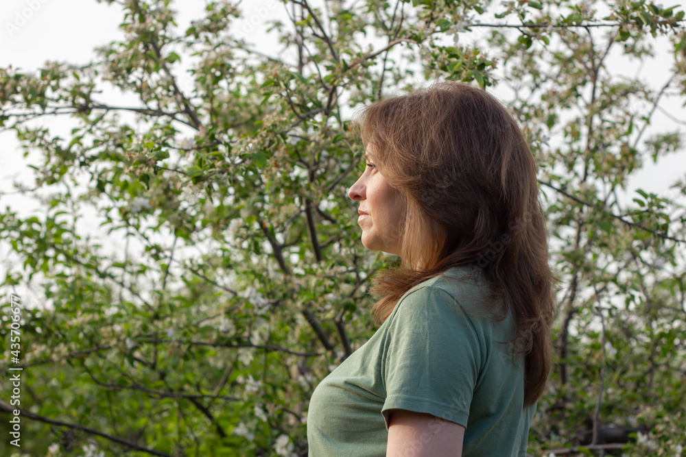 Beautiful attractive girl walking outdoors among the blossom apple trees. Beautiful attractive girl walking outdoors among the blossom apple trees.