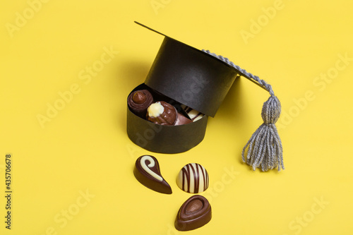 Graduation cap in the form of a box. A box of chocolates, black, milk chocolate. High school graduation. Color background