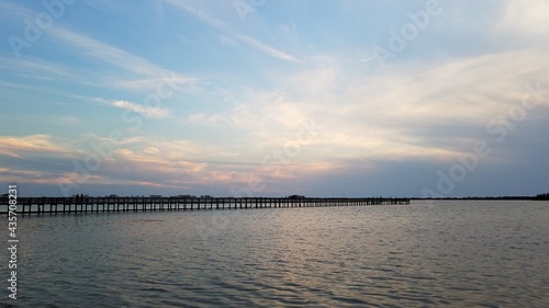 Pastel pink and blue clouds over a wooden fishing pier at sunset