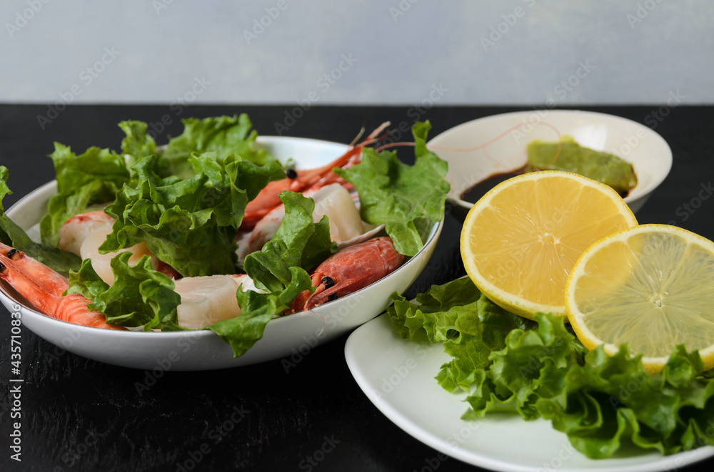 Natural raw scallop with boiled shrimp in the sink in a ceramic bowl with lettuce leaves and sauce on a dark background. Natural raw scallop with boiled shrimp in the sink in a ceramic bowl with lettuce leaves and sauce on a dark background.