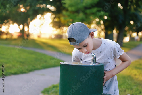 Fotografie Boy drinks tap water from public drinking fountain
