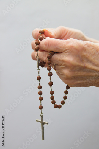 A woman holds a Christian rosary on white background