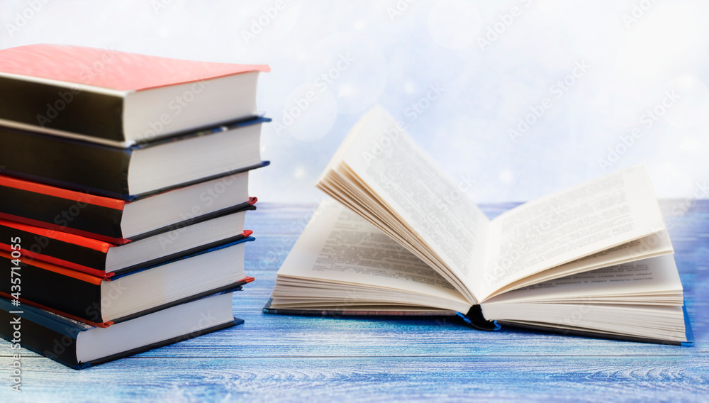 a stack of books and an open book lie on a blue wooden table a stack of books and an open book lie on a blue wooden table