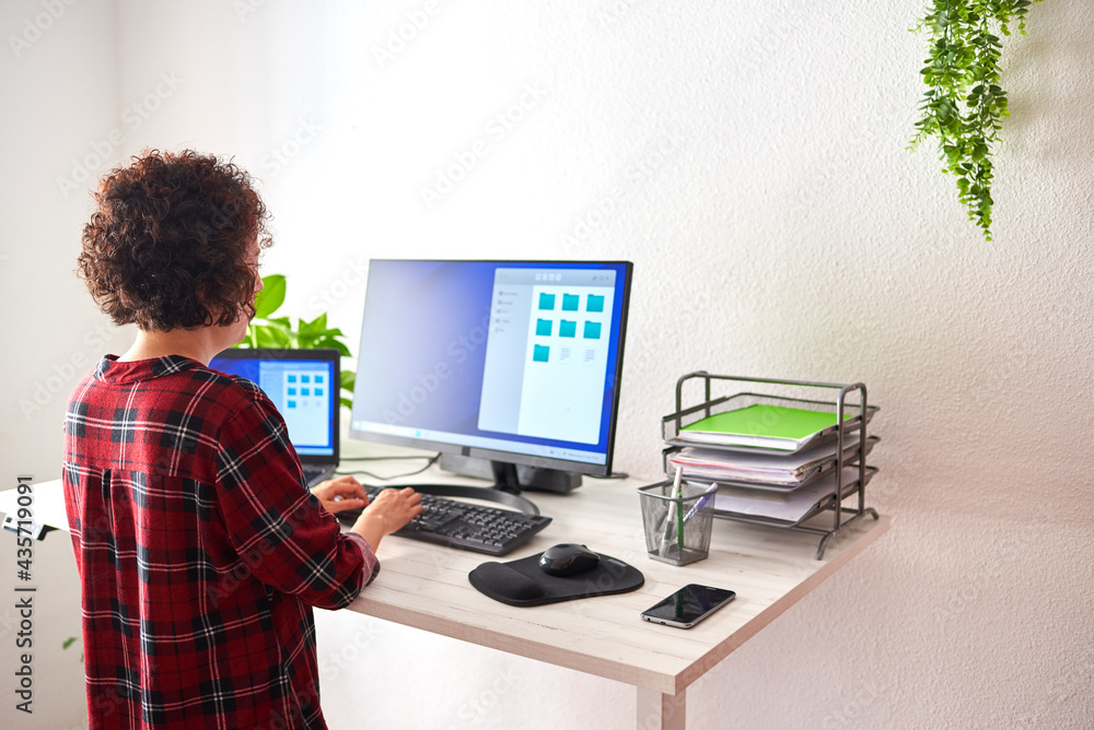 Woman typing on computer at adjustable standing desk