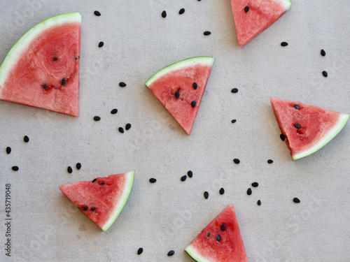 slices of watermelon and black seeds, summer pattern on pale pink background