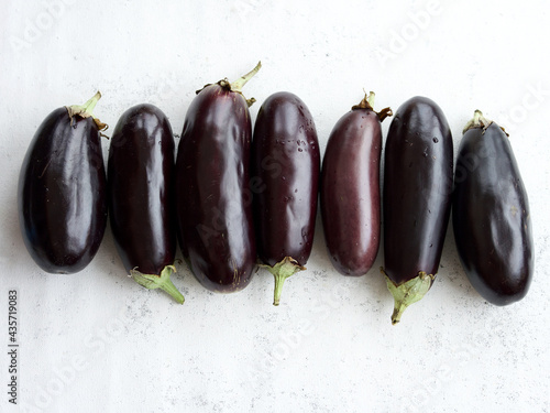 seven fresh eggplants on white background, top view