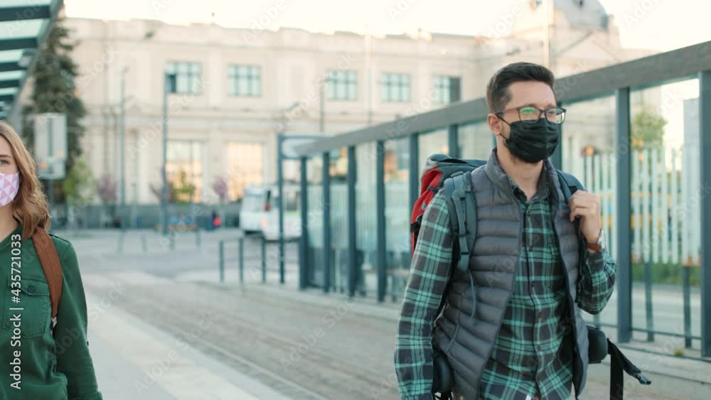 Portrait of diverse multi-ethnic young people with backpacks in masks walking outdoor in city. Caucasian couple travelling during coronavirus. Covid-19 pandemic, safe travel, tourism concept Portrait of diverse multi-ethnic young people with backpacks in masks walking outdoor in city. Caucasian couple travelling during coronavirus. Covid-19 pandemic, safe travel, tourism concept