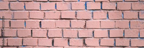 Old brick wall painted in pink. Texture of rough brickwork. Wide panoramic background with masonry.