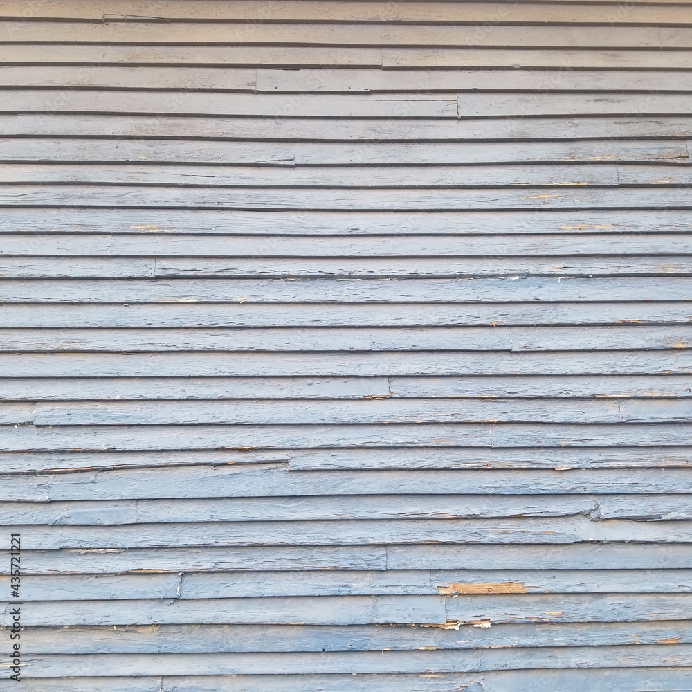 An entire side of a garage with worn grey wooden siding. An entire side of a garage with worn grey wooden siding.