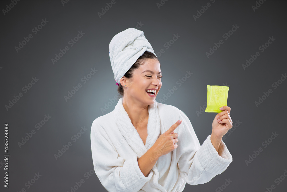 Daily pads for menstruation. Female in a bathrobe and towel points to a sanitary pad. She holds a female sanitary napkin absorbing an object that a woman wears during menstruation. Bleeding protection Daily pads for menstruation. Female in a bathrobe and towel points to a sanitary pad. She holds a female sanitary napkin absorbing an object that a woman wears during menstruation. Bleeding protection