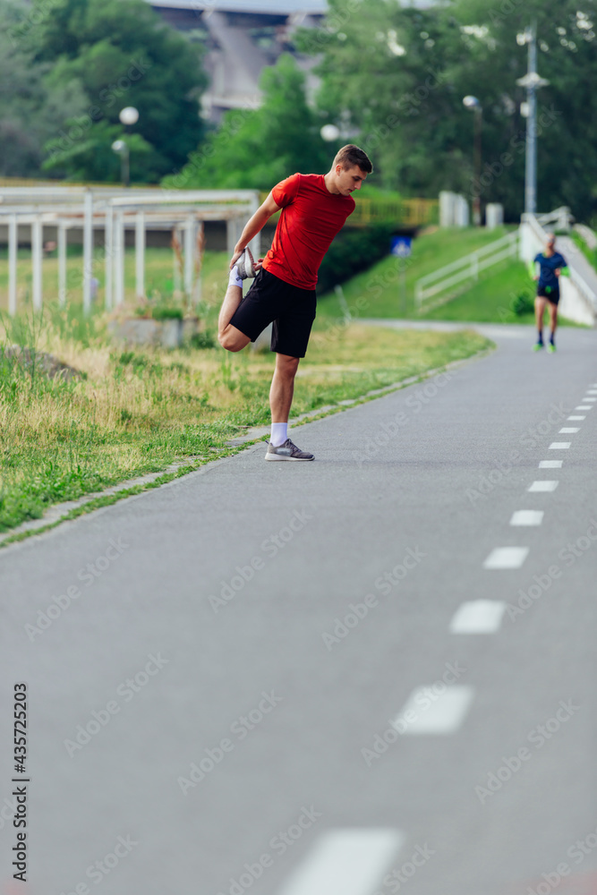 Handsome young man stretching and warming up before for morning workout  in the park