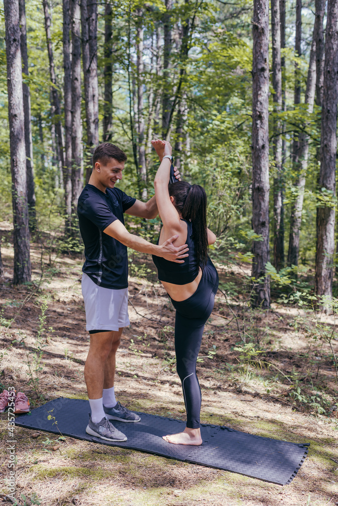 A beautiful young fitness couple is preparing for stretching before running in the forest.