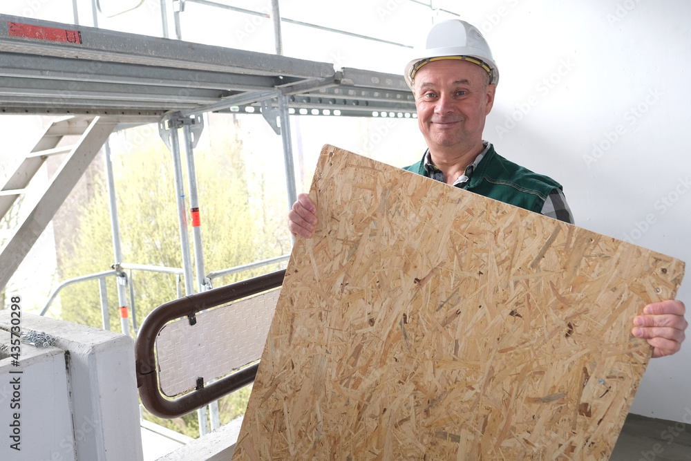 funny elderly builder with building materials in a white helmet
