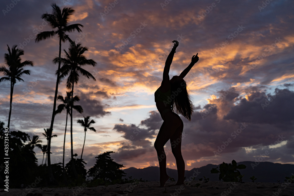silhouette of woman during Tropical Sunset With Palm Tree and dramatic clouds. Vacation and travel concept.