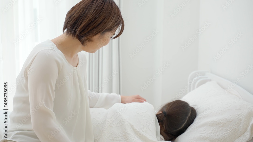 ベッドに横たわる娘を見守る母 ベッドに横たわる娘を見守る母