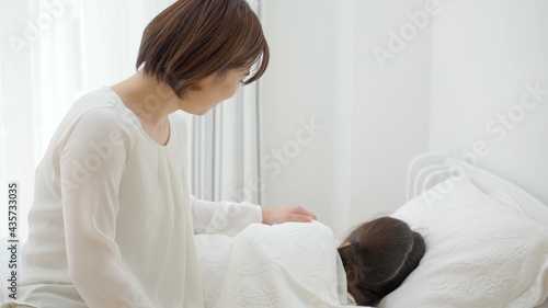 ベッドに横たわる娘を見守る母