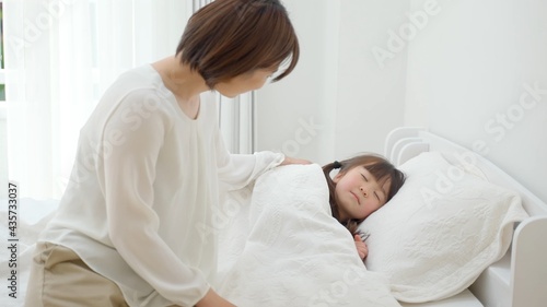 ベッドに横たわる娘を見守る母