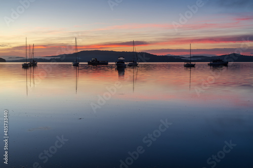 Sunrise waterscape with boats, light cloud and fog