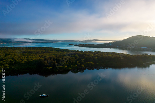 Early morning aerial waterscape with boats  light cloud and fog