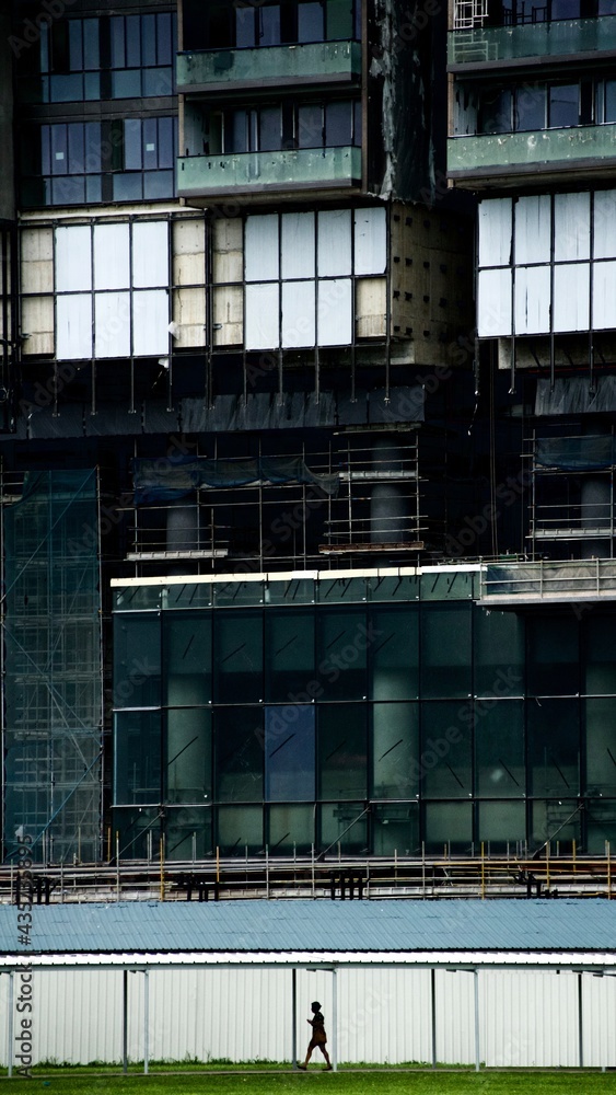 Lady walking alone under huge constructed building in Singapore