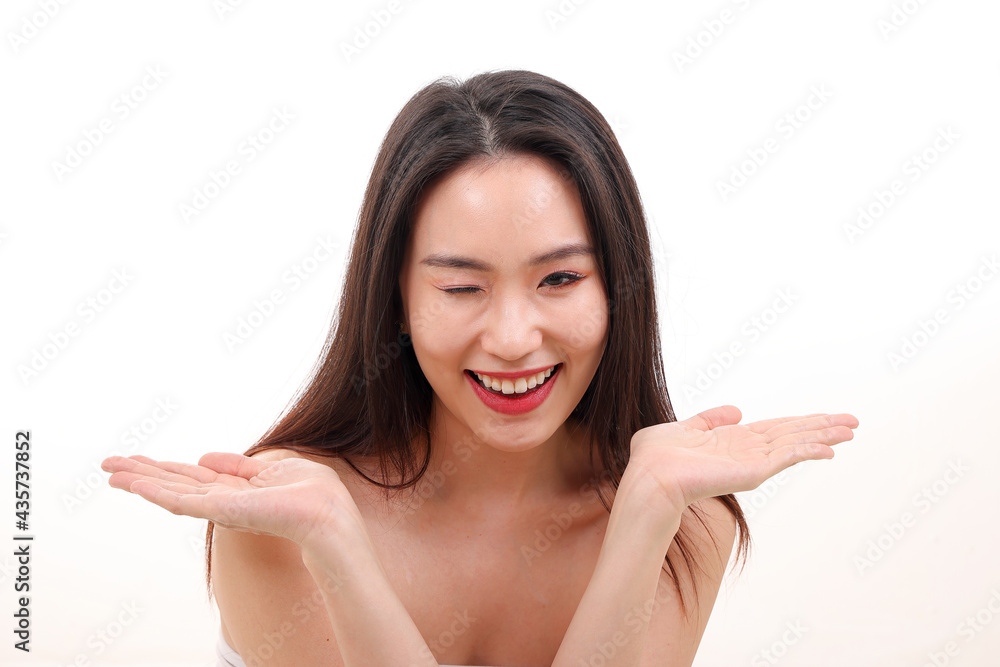 Beautiful young south east Asian woman posing holding hands palms up flat show display offer see white background wink Beautiful young south east Asian woman posing holding hands palms up flat show display offer see white background wink