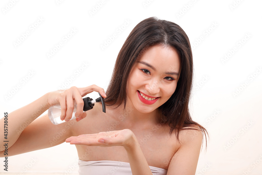 Beautiful young south east Asian woman posing holding using squeeze transparent liquid hand sanitizer plastic bottle pose see offer white background Beautiful young south east Asian woman posing holding using squeeze transparent liquid hand sanitizer plastic bottle pose see offer white background