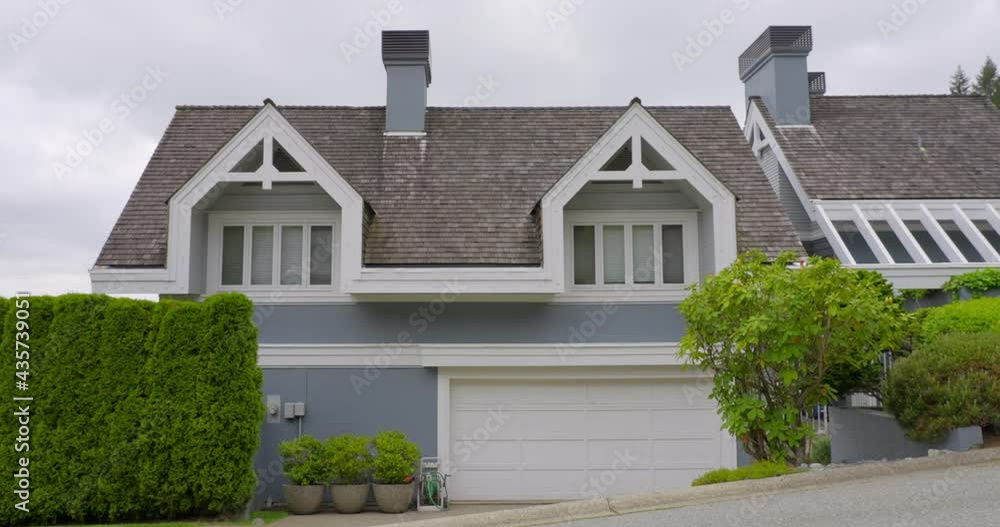 Establishing shot of two story stucco luxury house with garage door, big tree and nice landscape in Vancouver, Canada, North America. Day time on May 2021. ProRes 422 HQ. Establishing shot of two story stucco luxury house with garage door, big tree and nice landscape in Vancouver, Canada, North America. Day time on May 2021. ProRes 422 HQ.