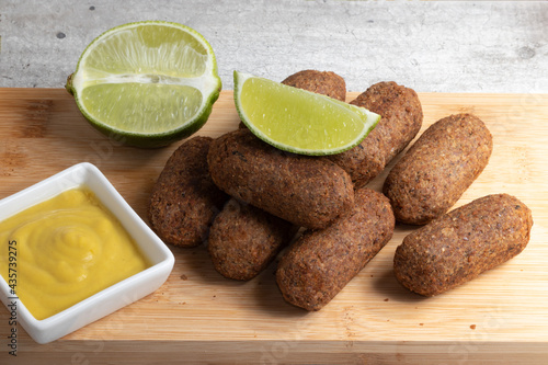 Kibbeh with lemon and mustard on cutting board
