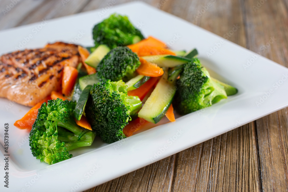 A view of a plate of grilled salmon, featuring steamed vegetables. A view of a plate of grilled salmon, featuring steamed vegetables.