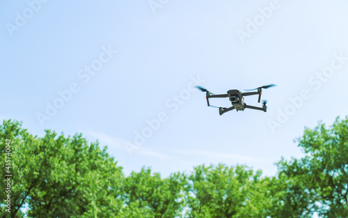 quadcopter on takeoff against green trees and blue sky. closeup view